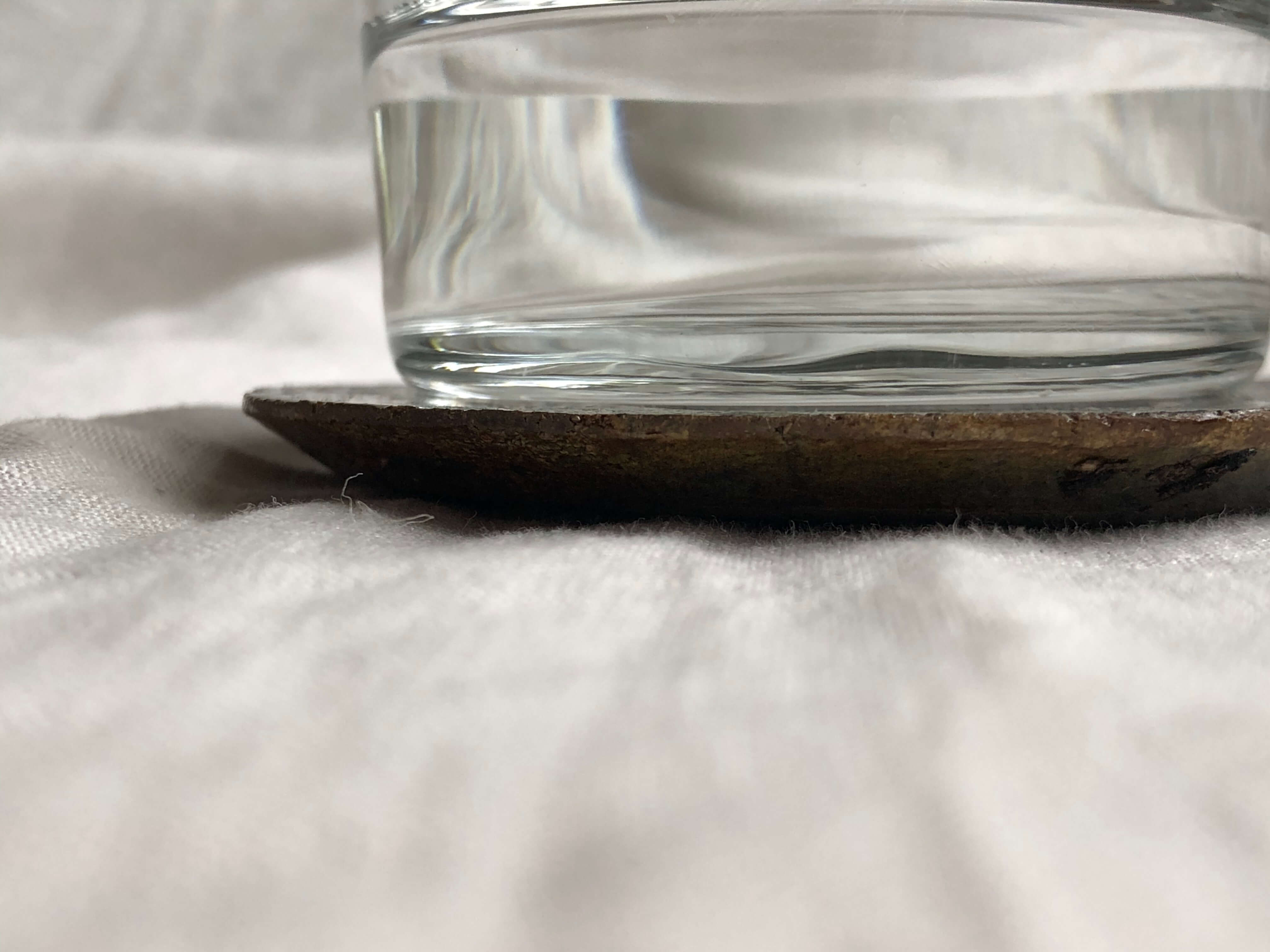 a close-up of a ceramic coaster with a water glass on it